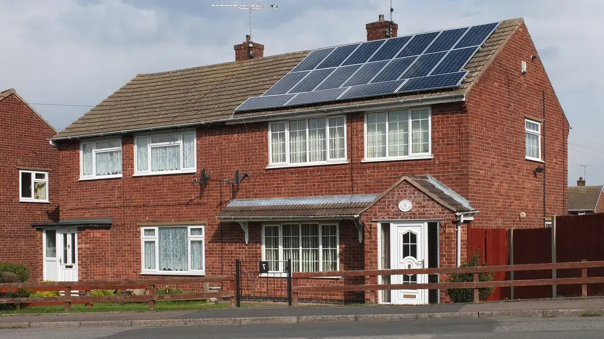 Brick family home in England with a row of black solar panels on the roof