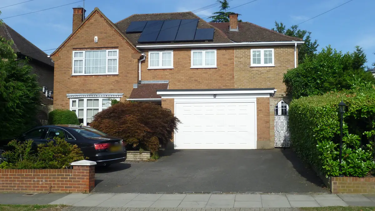 Detached brick house in north London with solar panels on the roof above the garage